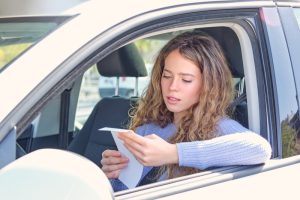 Driver sitting in her car reading a careless and imprudent driving ticket in Missouri